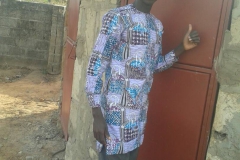 Yusupha het schoolhoofd bij één van de deuren van het nieuwe toiletgebouw